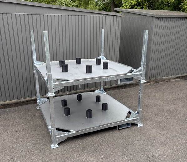 Maßgefertigte Sonderregalanlage aus Metall mit zwei Ebenen und Aufnahmevorrichtungen für Bauteile, aufgestellt im Außenbereich vor einer grauen Hallenwand.