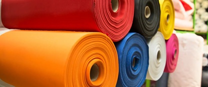 Stoffrollen in verschiedenen Farben, darunter Rot, Orange, Blau, Schwarz, Gelb, Weiß und Pink.
